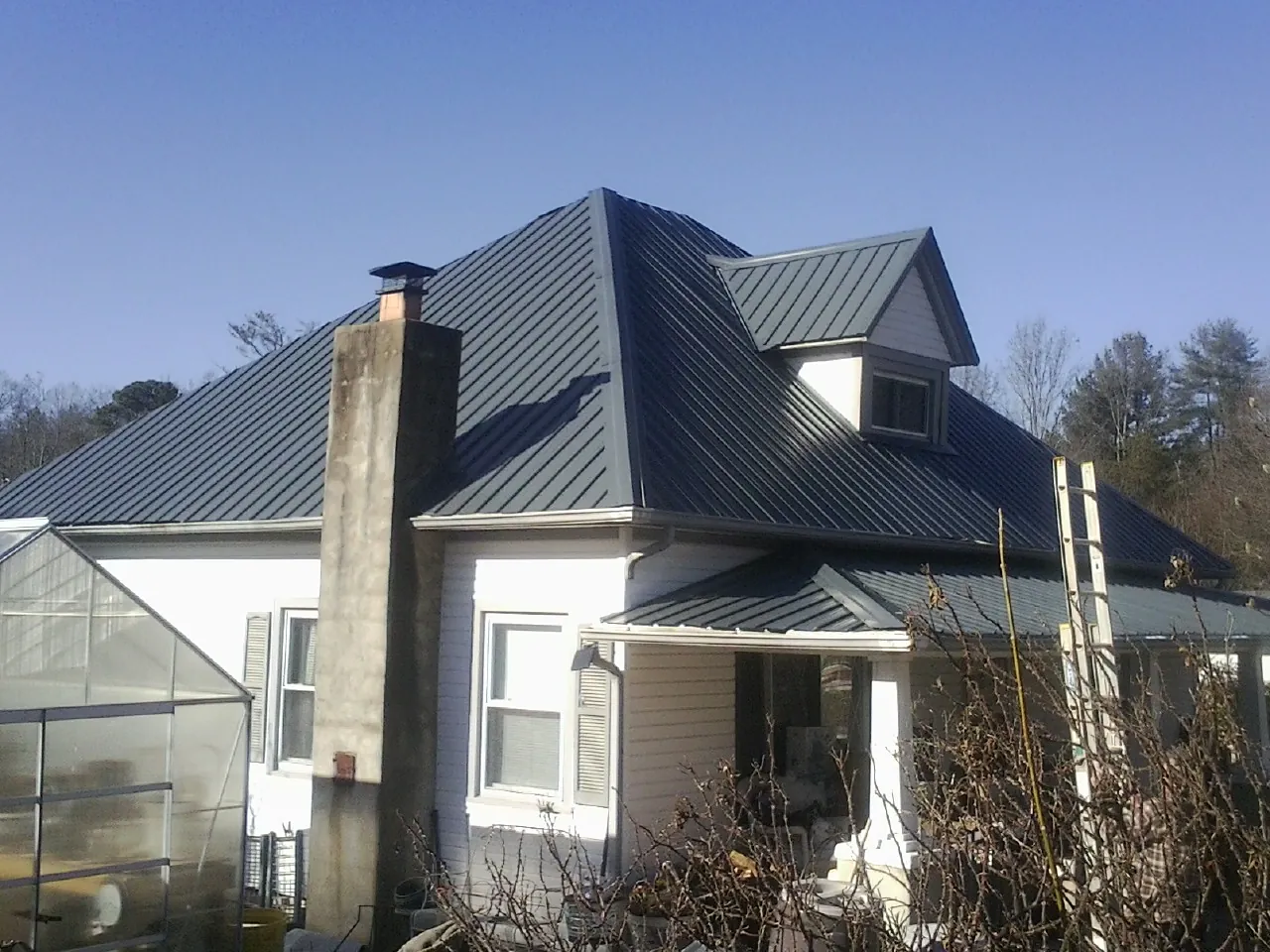 Dark blue standing seam metal roof on a white farmhouse with dormer — Slate & Tile Roof Repair by Roofing Brothers in Palo Cedro