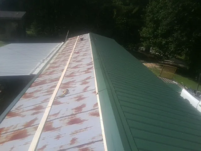 Old rusted panels beside newly installed green metal roofing — Wind Damage Roof Repair by Roofing Brothers in Palo Cedro