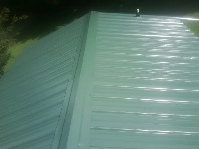 New green metal panels meeting at the ridge of a roof — Flat Roof Repair work by our crew in Palo Cedro