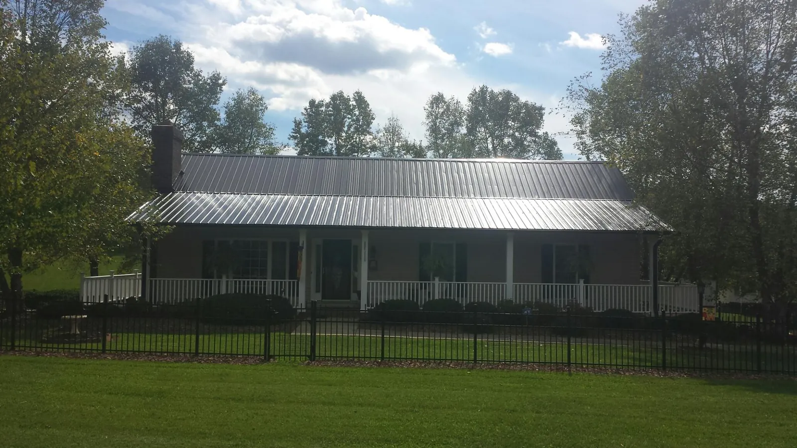 Gray metal roof on a brick ranch with a full width front porch — Gutter Guard Installation work by our crew in Palo Cedro