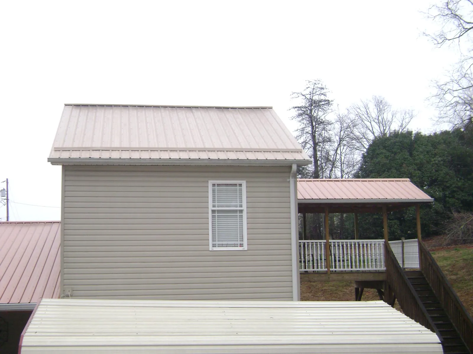 Tan metal roofs on a two story addition and attached porch, from a Roof Replacement job in Palo Cedro
