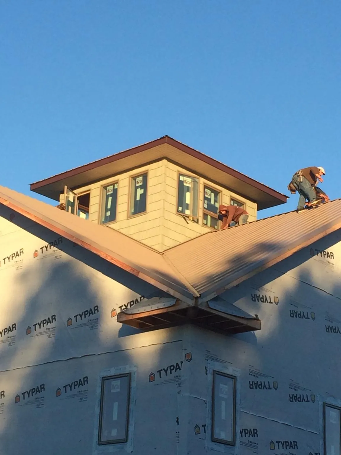 Roofers working around a rooftop cupola on a new metal roof at sunset — Roof Waterproofing in Palo Cedro by Roofing Brothers